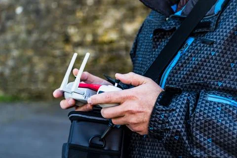 Man piloting a drone using a controller equipped with a joystick and a mobi.. Stock-Fotos