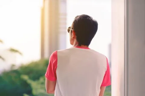 Man in pink and white t-shirt looking outside at sunset. Foto stock