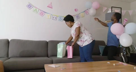 Man in pink shirt decorating table with balloons and flowers for celebration, at Video stock 316744288