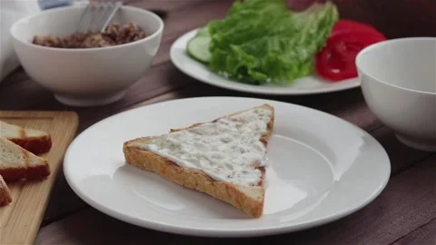 Man place lettuce leaf on bread with cream cheese making sandwich Stock Footage 109037671