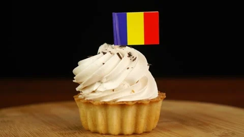 Man places decorative toothpick with flag of Romania into cream cake. National Stock Footage 159828076