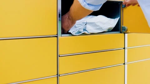 Man places a package into a yellow parcel locker. Contactless delivery and conve Stock Footage 342053531