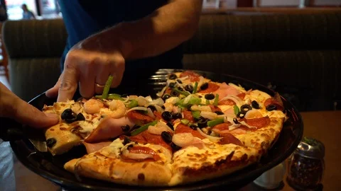 Man places a slice of shrimp ham and vegetable pizza on his plate in restaurant Stock Footage 85575000