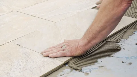 A man places a tile on the floor on top of cement. Stock Footage 88327478