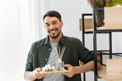 Man placing aroma reed diffuser to shelf home Stock Photos
