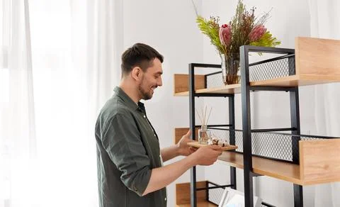 Man placing aroma reed diffuser to shelf home Stock Photos
