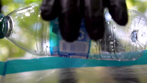 Man Placing Bottle Into Plastic Recycle Bag - Bottle in Focus 스톡 동영상 142012805
