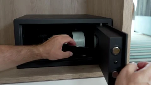 Man placing camera, smartphone inside hotel safe, entering security code. Stock Footage 341854218