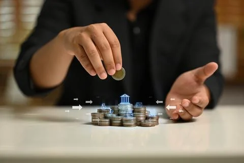 Man placing a coin on top of stack of coins with various financial icons Stock Photos