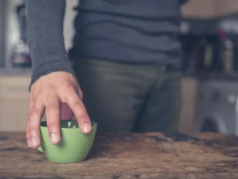 Man placing cup on table in kitchen Foto stock