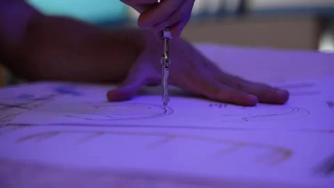 A man placing a drawing compass on a page filled with diagrams and using Video stock 284720298