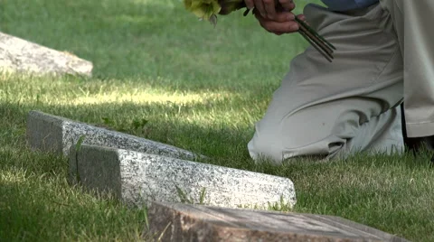 Man placing flowers on a grave, close up shot Stock Footage 66495324