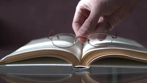 Man Placing Glasses on Open Book Video stock 153483027
