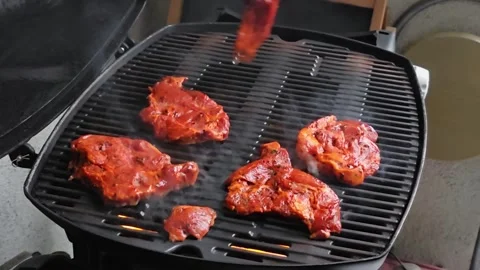 Man placing a marinated beef steak onto a hot barbecue grill, outdoor cooki.. Video stock 342747765