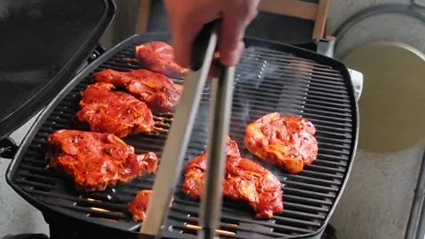 Man placing a marinated beef steak onto a hot barbecue grill, flames rising.. Video stock 344768095