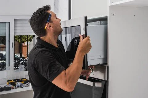 Man placing a microwave inside the hole of a new kitchen cabinet Stock Photos