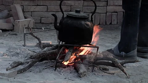 Man Placing an Old Burnt Teapot on the Fire on a Rustic Farm Stock Footage 289144741