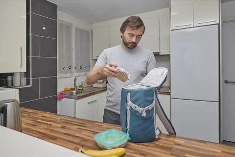 Man placing packed sandwich into backpack preparing food for trip Stock Photos