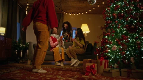 Man Placing Present under Christmas Tree with Multiethnic Friends Stock Footage 344399742