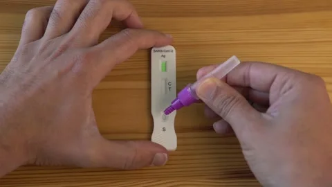 Man placing sample into covid-19 antigen test deviceand with a positive result Stock Footage 170759288