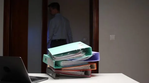 Man placing stack of colorful binders on office desk Stock Footage 322911846