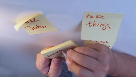 Man placing sticky notes on wall in close-up view, organizing handwritten Stock Footage 333769039