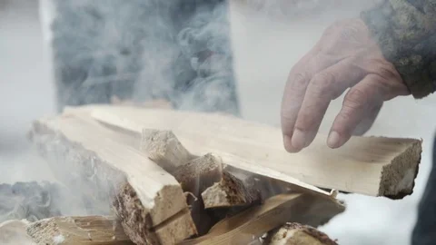 Man placing a tin container on a pile of burning wood Stock Footage 79792086
