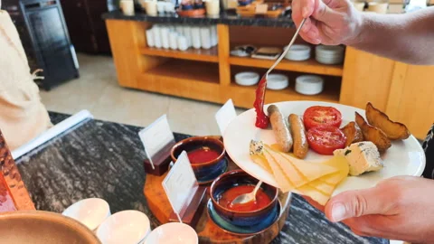 A man is placing tomato sauce on the side of a breakfast plate. Stock Footage 318473750