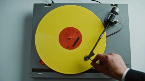 Man placing vinyl record on classic gramophone in apartment starting playback Stock Footage 332622976
