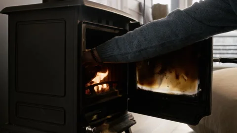 Man Placing Wooden Log into Burning Fireplace Stove Stock Footage 341303418
