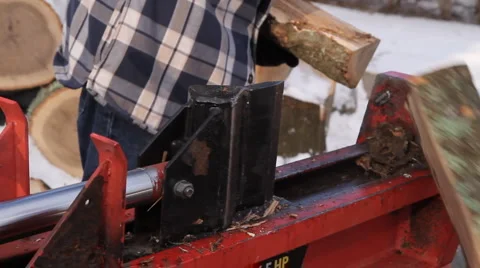 Man in plaid jacket splits wood using a hydraulic wood splitter in the snow Vidéo 1008948
