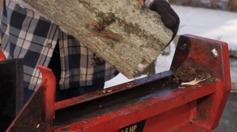 Man in plaid jacket splits wood using a hydraulic wood splitter Stock Footage 1008951
