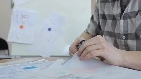A man in a plaid shirt, a pair of scissors cuts tracing paper which shows plan Video stock 66184663