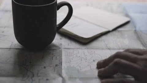 Man Plans Journey On Map And Notebook And Drinks Coffee 库存影片 142127962