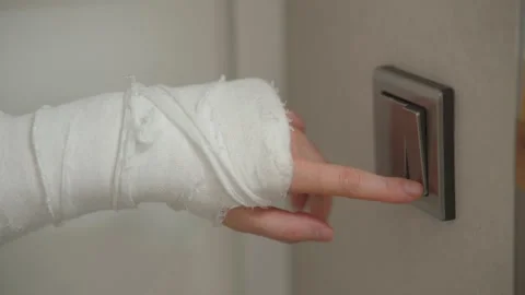 Man with plaster cast on arm presses the light on or off button Stock Footage 234550432