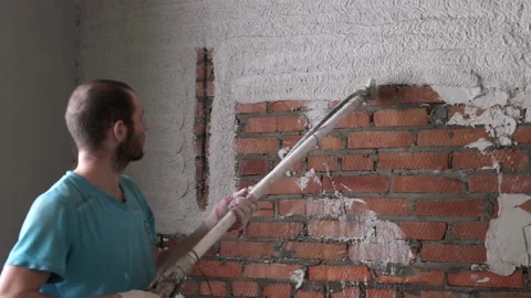 Man Plastering Brick Walls Using An Automatic Construction Gun. Building. Putty Stock Footage 168355344