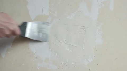 A man is plastering a damaged wall in a room with a hand trowel. Stock Footage 241933256