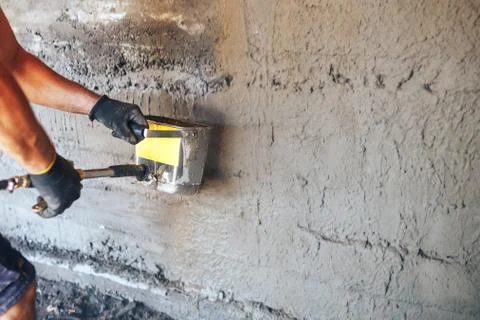 Man plastering a wall with mortar using a hopper bucket Stock Photos