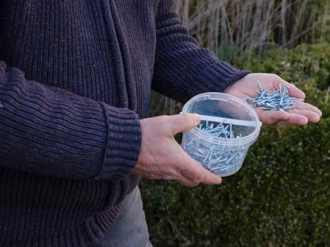 Man with a plastic tray filled with small new screws the right hand hold the Stock Photos