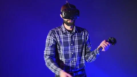 Man play 3D virtual reality game. Waving swords with controllers in VR game. Man Stock Footage 99969430