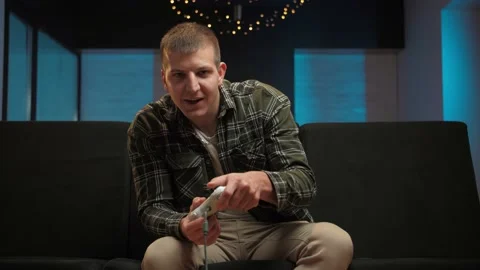 Man play video game sitting on couch in living room.Portrait of young guy Stock Footage 225653471