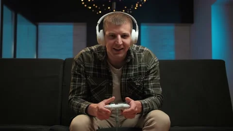 Man play video game sitting on couch in living room.Portrait of young guy with Stock Footage 225654947