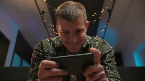 Man play video game on smartphone sitting at home.Portrait of young guy holding Stock Footage 225655585