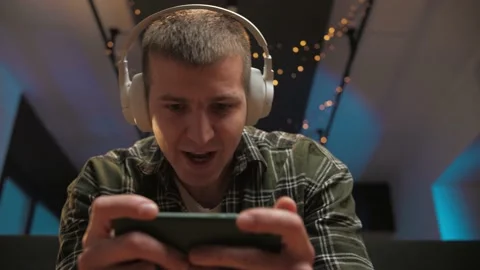 Man play video game on smartphone sitting at home.Portrait of young guy holding Stock Footage 225656291
