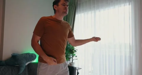 Man playfully gesturing near window in casual home setting with Stock Footage 305927681