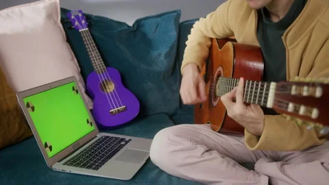 Man playing acoustic guitar. Tutorial with laptop computer and green screen Stock Footage 149604419