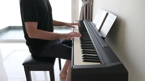Man playing and learning piano Stockbeeldmateriaal 164729647