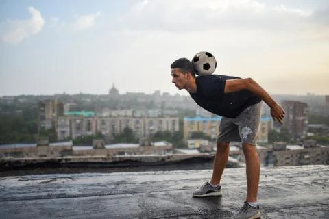 Man playing with ball outdoors on the roof on the background of the city Stock Photos