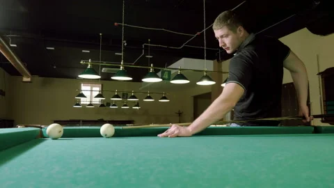 Man playing billiards, hitting balls with cue into pockets on billiard table. 4K Stock Footage 109412096