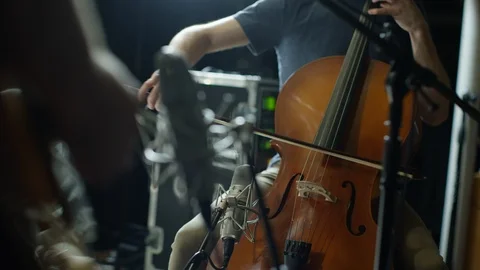 Man playing cello with guitar player in foreground Stock Footage 108936902